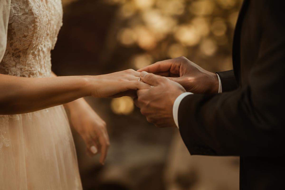 Close view of a couple exchanging rings in warm golden light